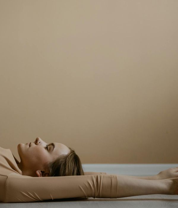 Woman in a calm yoga pose against a soft violet background.